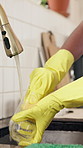 Hands, dishes and cleaning in kitchen, home and gloves for dirt, bacteria and safety with sponge. Person, faucet and routine for washing glass for germs, ppe or cloth with hygiene at apartment