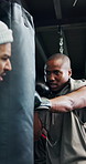 Boxing, coach and man with punching bag for training, workout or challenge with power. Trainer, boxer and gym for combat sports, fight practice and help with exercise for self defense in health club