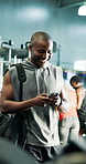 Happy, fitness or man in gym with phone, text message or workout for muscle development. Exercise, digital communication or African bodybuilder  with smile for strength training, dedication or mobile