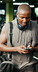 Typing, phone and black man walk in gym for social media, text message or training schedule. Mobile, person and leave sports club with chat app, internet communication and fitness information online