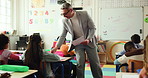Mature man, teacher and documents with test in elementary school for learning assessment or exam. Male person, educator or moderator with paperwork or learners for youth development in classroom