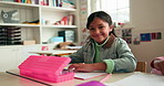 Happy, writing and face of child in classroom at elementary school for learning, growth or development. Smile, education and portrait of girl kid student with assessment, test or project at academy.