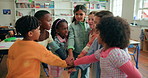 Kids, teamwork and stack hands for education, support and learning in elementary school. Children, celebration and happy group of students with cooperation, clapping and success together in classroom
