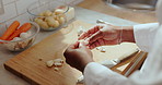 Hands, chef and peeling garlic for cooking, organic diet or cuisine in kitchen. Person, vegetable clove and food preparation in restaurant for culinary process, vegetarian and natural ingredients