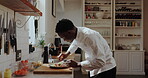 Black man, chef and plating food in kitchen for presentation,  culinary skills and herbs for flavor. Male person, cooking and garnish steak of lunch service, meat process and prepare cuisine at house