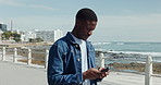 Beach, walking and black man with smartphone, travel and internet with message to contact. Social media, ocean and person with cellphone, vacation and online chatting with app or texting in Miami