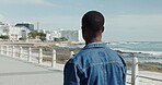Back, black man and walking on beach for travel, morning fresh air and holiday trip in nature. Male person, promenade and journey on vacation, ocean sightseeing and explore for stress relief on trip