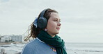 Thinking, woman and walk with headphones at beach for journey, holiday vision and listening to music. Thoughts, female person and travel for fresh air, streaming podcast and reflection for vacation