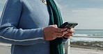 Mobile, hands typing and woman by ocean for travel, vacation or text on holiday. Phone, promenade and tourist outdoor for message on internet, walk and communication online with app for social media