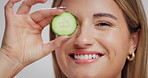 Woman, skincare and cucumber with face in studio, smile and mockup space with nutrition on white background. Girl, model and happy with organic fruit for detox, diet benefits and beauty in Spain