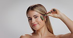 Woman, face or skincare with jade roller in studio for skin wellness on a white background. Portrait, female person or model with space, makeup or beauty tool for facial massage or lymphatic drainage