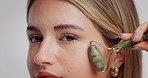 Beauty, girl and jade roller on face in studio for lymphatic drainage, skin glow and anti aging. Cosmetics, person and skincare tool on white background for puffiness reduction and detox circulation