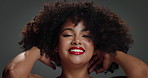 Face, hair care and woman in studio, shake head and confidence on grey background. Portrait, curls and happy person with volume, shine and beauty with glow, wellness and treatment with cosmetics