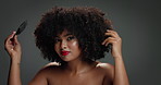Portrait, hair care and woman in studio with brush, beauty and vibrant for aesthetic. Happy, face and model in gray background with confidence, empowerment and bold with comb for natural volume afro