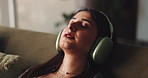Woman, headphones and tired with music on sofa, eyes closed and rest with streaming service at home. Person, sound and audio subscription, inspiration and relax on couch in living room at apartment
