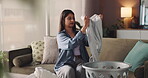 Folding, laundry and clothes with woman on sofa for cleaning, maintenance and fresh linen. Domestic chores, packing and basket with person in living room of home for housekeeping and washing