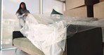 Woman, sofa and unpacking with cover in new home for furniture investment or property in apartment. Female person, homeowner or checking quality with couch, boxes or interior for fresh start in house
