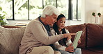 Grandmother, girl and tablet on sofa with smile, bonding or problem solving game with care at home. Senior woman, child and tech for talk, point or learning with puzzle, happy and app at family house