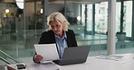 Business, woman and reading document in office for audit, finance report and company budget. Mature person, laptop and paperwork with financial comparison, funding information and investment proposal