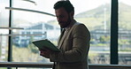 Business, man and reading on tablet in lobby for accounting, finance report and budget review. Male person, digital and typing for research, financial planning and information for funding investment