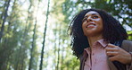 Backpacking, adventure and woman with smile, forest or hiker in nature on break, fresh air or travel. Outdoor, traveller and African person on hike, low angle and happy for journey in woods and trip