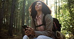 Break, thinking and woman with phone for hiking, typing post or social media connectivity in forest. Relax, scroll and happy hiker with mobile app for trekking, navigation or online search in woods