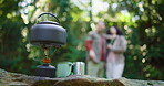 Camping, stove and kettle with couple in nature for brewing coffee, trekking rest stop and help. Adventure holiday, gas canister and tea pot with people and cooking equipment in forest for travel