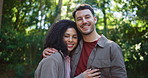 Happy couple, hiking and face with hug in forest, excited or outdoor with tourism on summer holiday. People, man and woman with embrace, care and portrait for trekking with interracial love in woods