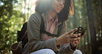 Hands, texting and phone in forest, hiking or check map for landmark, location and relax in summer. Woman, smartphone and mobile app for break on log with trekking, adventure and smile in Brazil