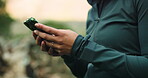 Athlete, typing and hands with smartphone in forest, web or check progress on fitness app in nature. Outdoor, wellness and  person with mobile for workout goals, browsing and online on break in woods