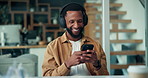Black man, phone and texting with headphones in home, happy or relax for streaming in lounge. African person, smartphone and smile with mobile app, audio or listen to music with subscription at house