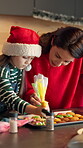 Cookies, frosting and Christmas with mother and daughter in kitchen for bonding, holiday season and help. Santa snack, support and festive dessert with woman and kid in family home for baking