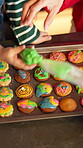 Cookies, frosting and hands with family in kitchen for learning, baking and dessert decoration. Teaching, biscuit snack and cooking with above woman and child for icing in home for support and help