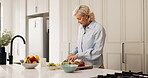 Cutting, food and fruit salad with woman in kitchen of home for diet, health or nutrition. Breakfast, chopping and cooking with mature person at counter in apartment for natural or organic meal prep