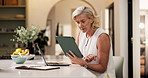 Tablet, laptop and mature woman in home with research for finance report with freelance career. Digital technology, computer and financial advisor with online budget planning in kitchen at apartment.