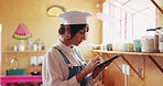 Woman, chef and tablet with research for online recipe, cooking class or checklist in cafeteria. Female person, culinary artist and checking jars of spices on shelf with technology for ingredients