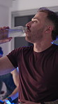 Man, cycling and drinking water with fitness at gym for intense training, stationary bike and wellness at club. Person, exercise and bicycle with bottle, group workout or challenge in cardio class