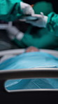 Hands, surgeon and group with patient in hospital bed, emergency room and equipment for service. People, doctors and process with surgery, saving life and procedure with healthcare job in theater