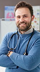 Face, doctor and man in office, arms crossed and wellness with peadtrician, smile and pride. Confidence, medical service and happy professional in hospital, stethoscope and about us with healthcare