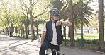 Man, delivery and checking watch with bicycle in park for deadline order or schedule package. Male person, time and wristwatch with backpack on bike for rush, commute or courier service in nature