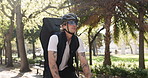 Man, bicycle and delivery with backpack in park for travel, package or parcel transportation in nature. Male person, commute or outdoor ride with bike, helmet or bag for eco friendly courier service
