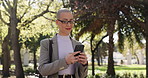 Business woman, walking and typing with phone in park for communication or outdoor network. Female person, texting or chat with mobile smartphone or app for travel, conversation or commute in nature
