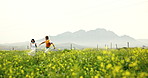 Running, love and couple in field of flowers with bonding, care and romance on countryside holiday. Happy, relationship and man with woman in nature on rapeseed farm on weekend trip together.