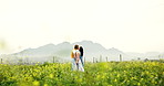 Couple, kiss and meeting on field, flowers and happy with sky, space and love in countryside in spring. Woman, man and walk in nature with holding hands, care and relationship with vacation in Greece