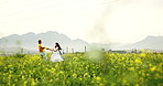 Spinning, love and couple in field of flowers with bonding, care and romance on countryside holiday. Happy, relationship and man with woman for playing on rapeseed farm on weekend trip together.