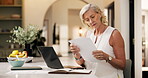 Typing, paper or mature woman in home with laptop, online research or editing of blog post. Reading, WFH and journalist in kitchen with document, information gathering or source feedback for article.
