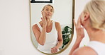 Hygiene, face cream and mature woman in bathroom for health, skincare or wellness treatment in home. Cosmetic, beauty and female person with moisturizer by mirror for facial dermatology in apartment.