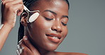 Black woman, jade roller and skincare in studio with self care, mock up space and circulation on background. African girl, model and smile with beauty, dermatology and massage for lymphatic drainage