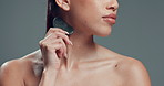Woman, skincare and neck massage with gua sha in studio for collagen on a gray background. Female person, model or beauty tool with stone for lymphatic drainage, anti aging or blood circulation
