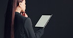 Business woman, thinking or studio with tablet screen for research or network on a dark background. Back view, female person or thoughtful employee with technology display or mockup space for new app